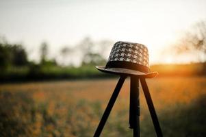 el sombrero de un joven se coloca en un trípode. con puesta de sol en el chapoteo de la tarde y hermoso foto