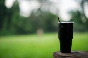 A glass of black water is placed on a wooden pole with a plug, the concept of drinking water and a glass of water. photo