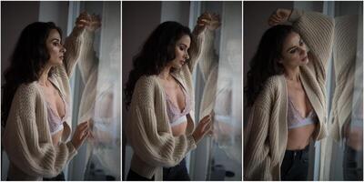 Attractive sexy brunette in white bra and brown sweater posing provocatively, near a window,studio shot. Portrait of sensual woman with long hair, in classic boudoir scene , looked out the window photo