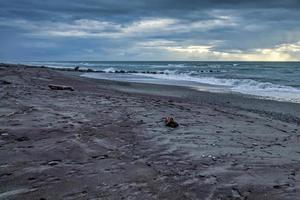 clima tormentoso acercándose a una playa desolada en nueva zelanda foto