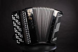 Russian folk musical instruments.Black Accordion isolated on a dark background photo