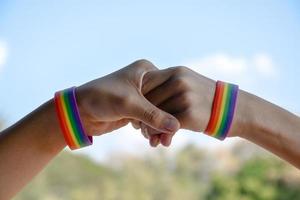 Rainbow rubber wristbands in wrists of asian boy couple with blurred background, concept for celebration of lgbt community in pride month or in June around the world. photo