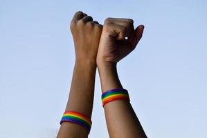 Rainbow rubber wristbands in wrists of asian boy couple with blurred background, concept for celebration of lgbt community in pride month or in June around the world.