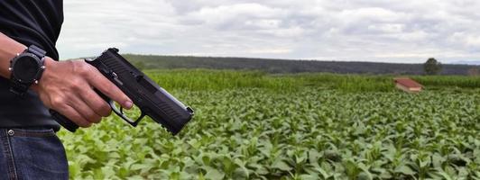 Pistola automática de 9 mm sujeta en la mano derecha del tirador, concepto de seguridad, robo, gángster, guardaespaldas en todo el mundo. enfoque selectivo en pistola. foto