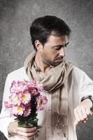 hombre enamorado de un ramo de flores mirando el reloj con preocupación. imagen vertical foto