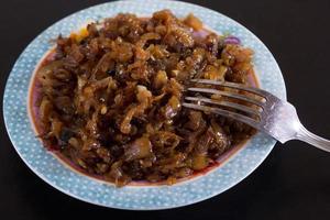 Close up caramelized onion on plate with fork on the black background photo