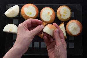 Top view of woman hands peeling off cutted in half unpeeled onion on the black background photo