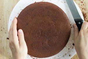 Baked chocolate sponge cake and hands with knife to cut photo