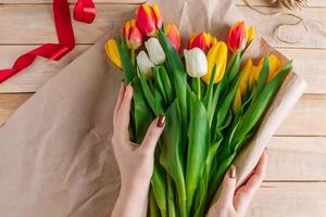 el proceso de envolver ramo de tulipanes frescos en papel artesanal ecológico.