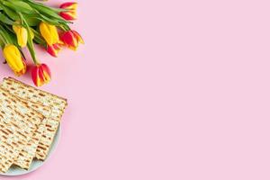 Happy Passover banner. Matzo and a bouquet of colorful tulips on a pink background. Traditional Jewish food for Pesach. photo