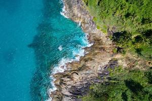Aerial view of sea crashing waves White foaming waves on seashore rocks Top view Rocky coast mountain landscape view Nature background photo