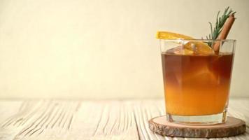 un verre de café noir americano glacé et une couche de jus d'orange et de citron décoré de romarin et de cannelle video