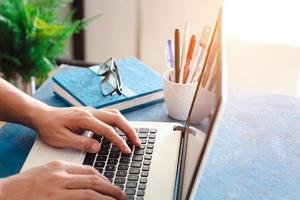 Close up shot of  male hands typing on laptop while sitting at office desk indoors, man fingers tapping and texting on computer keyboard while working in cabinet, Work concept. photo