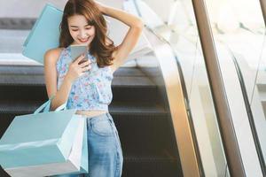 una joven asiática usa un teléfono móvil cuando va de compras