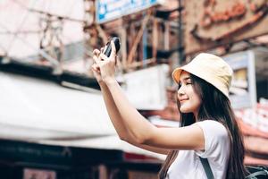 adulto joven viajero asiático feliz mujer sosteniendo cámara instantánea película foto