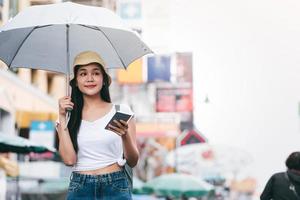 Young asia adult woman with umbrella use smartphone for travel in bangkok. photo