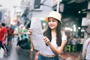 una joven viajera asiática adulta usa un mapa para explorar el área. foto