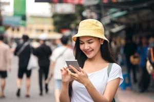 mujer viajera asiática que usa el teléfono móvil para la aplicación y el mensaje social de chat a través de Internet