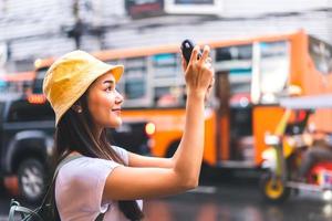 mujer viajera asiática tomando fotos con cámara instantánea