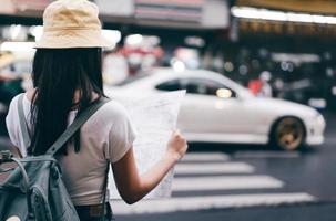 mujer asiática adulta usando mapa para mochila de viaje en solitario en bangkok. foto