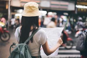 mujer asiática adulta usando mapa para mochila de viaje en solitario en bangkok. foto