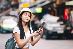 una mujer sola haciendo turismo con tecnología moderna usa un teléfono inteligente para un taxi.