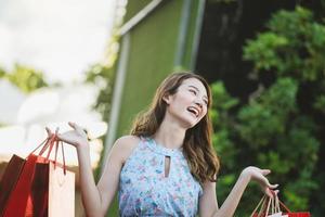 mujer asiática joven sonrisa disfruta comprando con una bolsa roja. foto