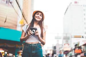 joven mujer asiática con cámara instantánea en bangkok, tailandia foto