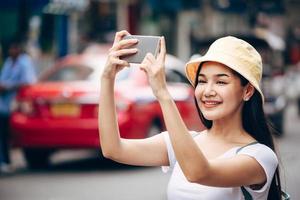 mujer adulta joven viajera asiática relajarse viaje con teléfono móvil foto