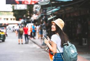 joven viajero asiático mujer feliz en camisa blanca con mochila. foto