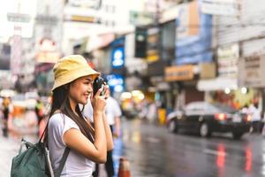 mujer viajera asiática tomando fotos con cámara instantánea