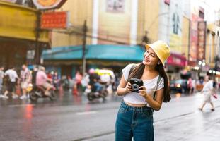 mujer viajera asiática tiene cámara instantánea foto
