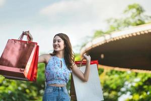 mujer asiática joven sonrisa disfruta comprando con una bolsa roja. foto