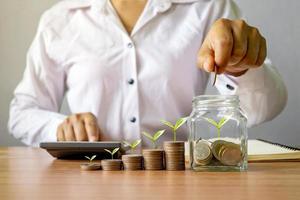 A businessman holds coins in a money jar and a tree grows on stacked coins. business growth concept, finance, investment photo