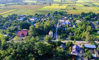 Aerial view of northern Thailand village with green pasture and lush green fields.