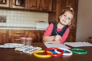 linda niña, adorable niño en edad preescolar pintando con acuarelas foto