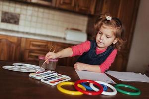 linda niña, adorable niño en edad preescolar pintando con acuarelas foto