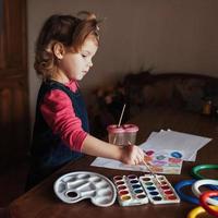 linda niña dibuja un círculo de pinturas de colores foto