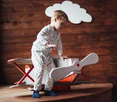 niño jugando con avión de madera foto