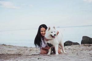 mujer jugando con su perro en la playa foto