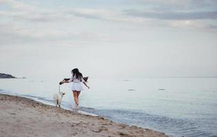 hermosa mujer joven caminando con su perro en la playa foto