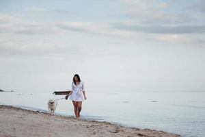 Young beautiful woman walking with her dog on the beach photo