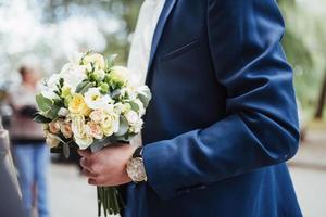 wedding bouquet in hands of the groom photo