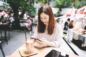 Young adult asian woman using smart phone at outdoor cafe on weekend photo