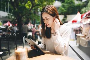 una mujer asiática de negocios adulta joven usa una tableta para hacer negocios en un café de estilo de vida de la ciudad al aire libre. foto