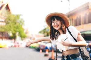 mujer asiática con gafas que viaja en bangkok y llama a un taxi. foto