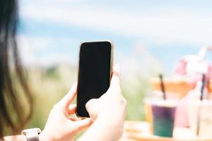 primer plano de la mano de una mujer joven usando un teléfono móvil para tomar una foto para la tecnología social.