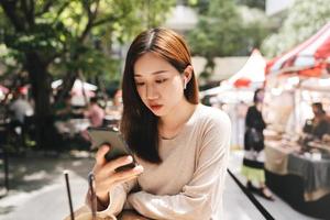 una mujer asiática de negocios adulta joven que usa un teléfono inteligente escucha música en el café el día. foto