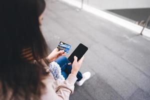 Rear view of  asian woman using smart phone for shopping online payment with app photo