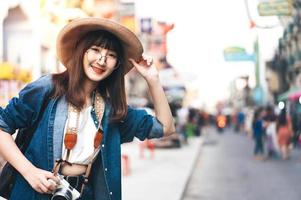 joven viajero asiático sonrisa gafas chica con cámara. foto